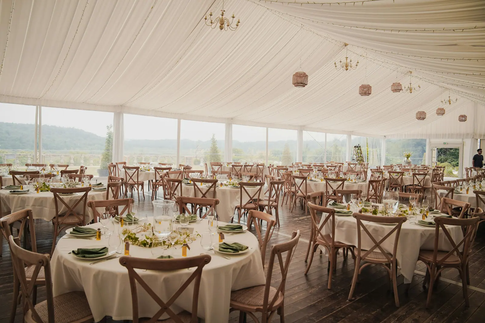 Interior de una carpa de boda con mesas redondas preparadas para el banquete