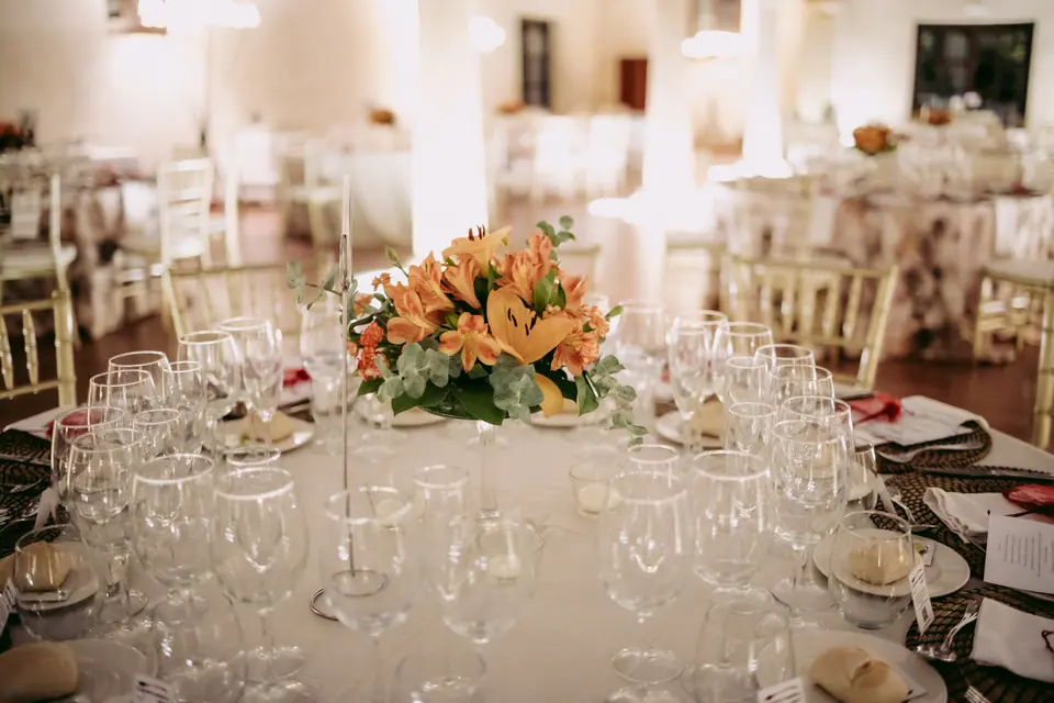 Centro de flores naranjas sobre una mesa de banquete con cristalería